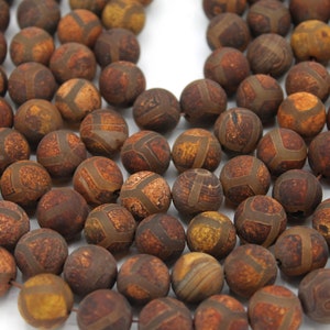 Puede incluir: Una hebra de cuentas de ágata marrón con intrincados patrones y un tono dorado. Las cuentas son redondas y lisas, perfectas para la elaboración de joyas.