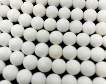 May include: A close-up of a collection of white round beads. The beads are arranged in a circular pattern, creating a visually appealing texture.