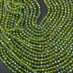 May include: A strand of green faceted glass beads. The beads are small and have a shiny, iridescent finish.