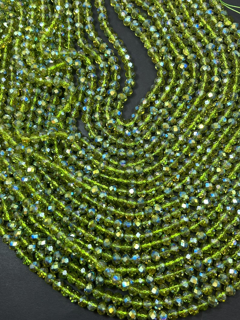May include: A strand of green faceted glass beads. The beads are small and have a shiny, iridescent finish.