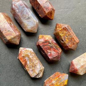 May include: Eight faceted, polished, red, brown, and gold tiger's eye gemstone beads. The beads are all roughly the same size and shape, and they have a smooth, polished finish.