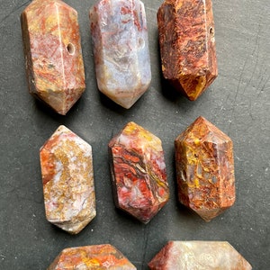 May include: Eight polished, faceted, red, white, and gold tiger's eye gemstone points with a hole drilled through the centre.