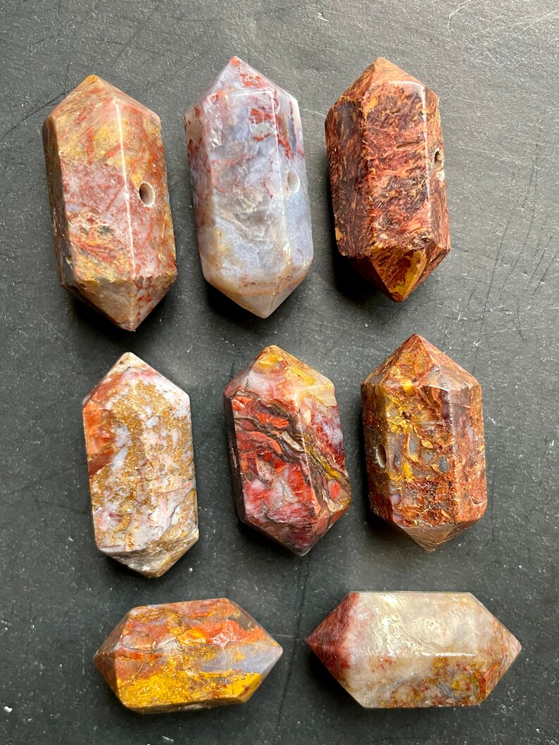 May include: Eight polished, faceted, red, white, and gold tiger's eye gemstone points with a hole drilled through the centre.