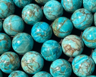 May include: A collection of turquoise-colored, round beads. Each bead has a unique pattern of brown veining, creating a marbled effect. The beads are smooth and polished, reflecting light. The overall theme is jewelry making or crafting supplies.