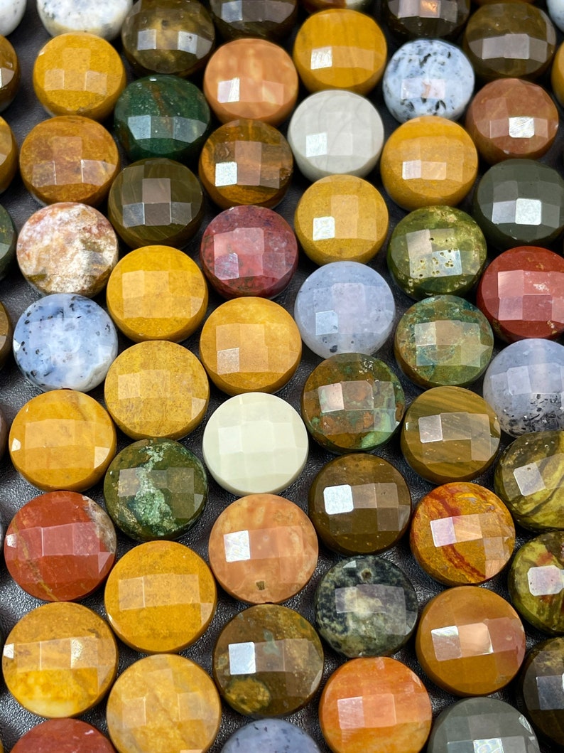 May include: A collection of round, polished stones with various patterns and colors, including brown, yellow, green, red, and white. The stones have a faceted, geometric design.