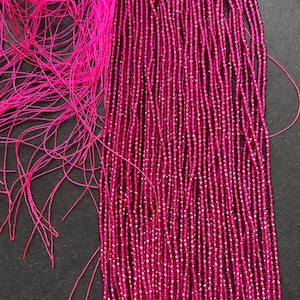 May include: A strand of pink ruby beads, approximately 20 inches long, with a faceted finish. The beads are strung on a thin thread and are ready to be used for jewelry making.
