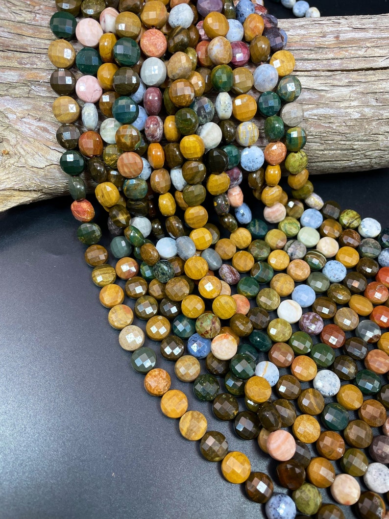 May include: A strand of multi-colored gemstone beads. The beads are round and faceted, with a variety of colors including brown, green, yellow, and red. The beads are strung on a clear cord.