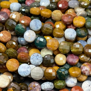 May include: A strand of colorful, faceted gemstone beads. The beads are round and have a variety of colors, including brown, green, red, and white. The beads are made of natural stone and have a polished finish.