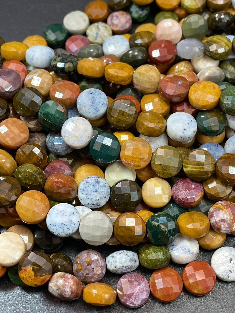 May include: A strand of colorful, faceted gemstone beads. The beads are round and have a variety of colors, including brown, green, red, and white. The beads are made of natural stone and have a polished finish.