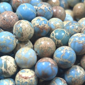 May include: A close-up of a pile of blue and brown jasper beads. The beads are round and have a mottled appearance.