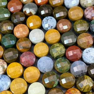 May include: A collection of round, polished gemstone cabochons in various colors and patterns. The stones are arranged in a grid pattern on a gray surface.