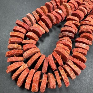 May include: Strands of coral-colored, disc-shaped beads. The beads are strung together, showcasing a natural, textured surface. The color varies from light to deep coral, with visible natural variations. The beads are likely for jewelry making.