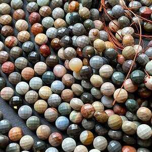 May include: A strand of faceted gemstone beads in various shades of brown, grey, and blue. The beads are round and have a smooth, polished finish.
