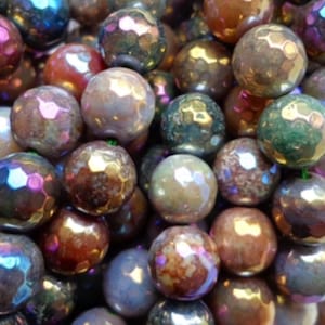 Peut inclure: Un brin de perles d'agate irisées avec une finition facetée. Les perles sont d'un mélange de couleurs brun, vert, violet et gris.