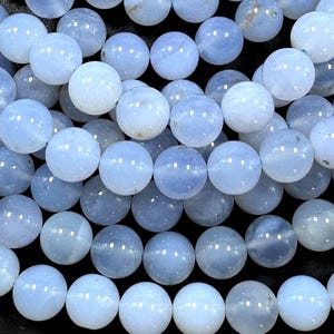 Pu&ograve; includere: Una collana di perle di agata blu chiaro. Le perle sono rotonde e lisce, con un aspetto leggermente traslucido.