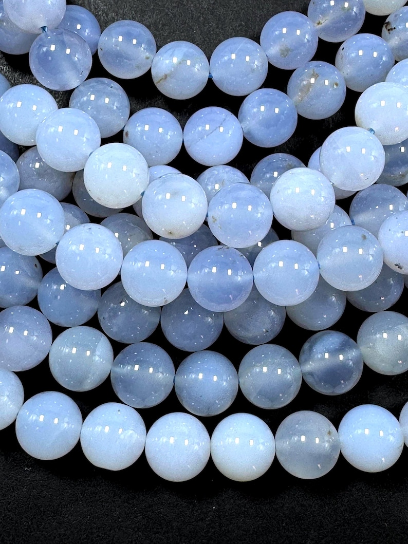 Pu&ograve; includere: Una collana di perle di agata blu chiaro. Le perle sono rotonde e lisce, con un aspetto leggermente traslucido.