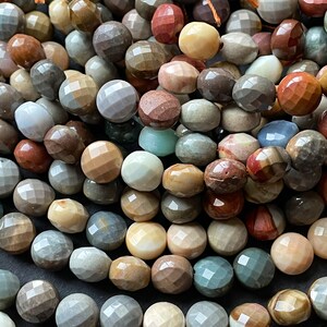 May include: A strand of faceted gemstone beads in various shades of brown, beige, grey, red, and green. The beads are all approximately the same size and have a smooth, polished finish.