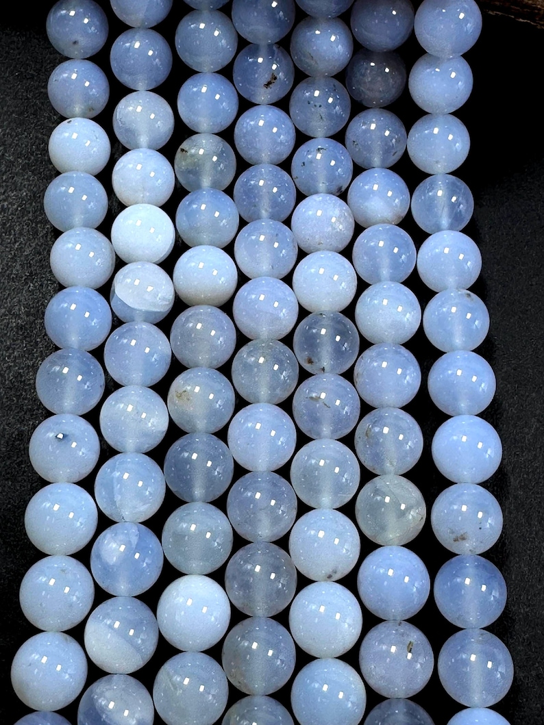 Pu&ograve; includere: Una collana di perle di agata blu chiaro. Le perle sono rotonde e lisce, con un aspetto leggermente traslucido.