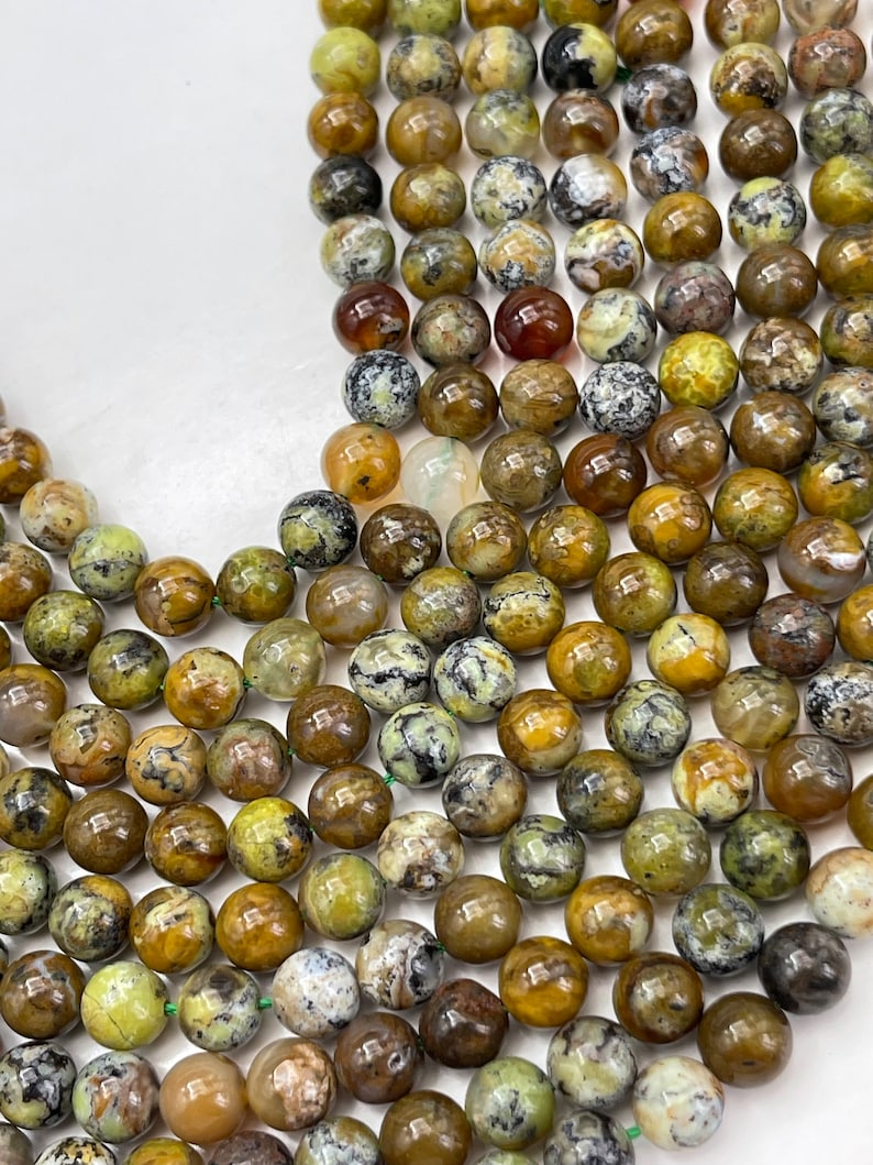 Op de afbeelding: Een streng ronde, groene, bruine en witte opaal kralen. De kralen zijn ongeveer 8 mm in diameter en hebben een natuurlijke, gepolijste afwerking.