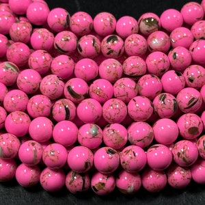 May include: A strand of pink and brown round beads. The beads have a marbled effect with white and black swirls.