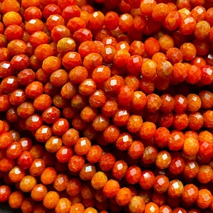 K&ouml;nnte beinhalten: Eine Str&auml;hne orangefarbener Korallenperlen, jede Perle ist facettiert und hat eine strukturierte Oberfl&auml;che.
