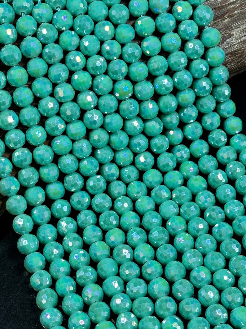 May include: A strand of turquoise blue faceted glass beads. The beads have a slightly iridescent finish.
