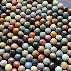 May include: A strand of multi-coloured, faceted gemstone beads. The beads are round and have a variety of brown, grey, red, and yellow tones.