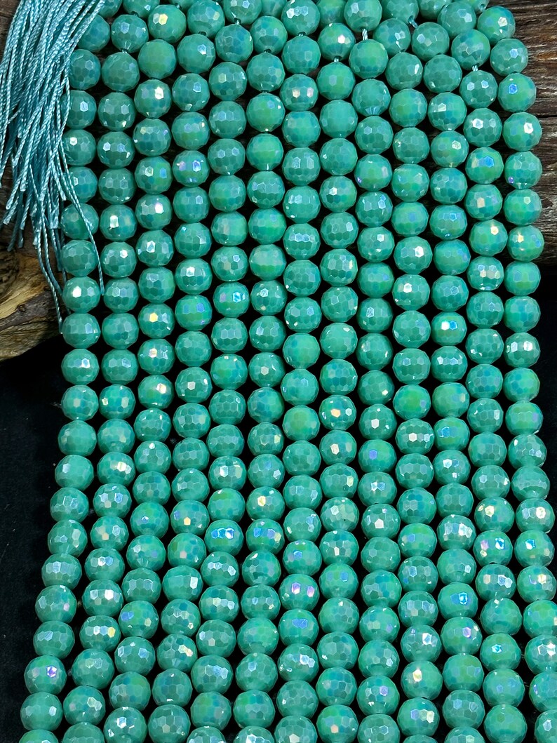 May include: A strand of teal green faceted glass beads. The beads have a iridescent finish.