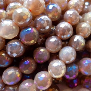 May include: Close-up of a collection of iridescent, faceted beads in shades of beige, cream, and purple. The beads have a textured, geometric surface and are round in shape. These beads are suitable for jewelry making.