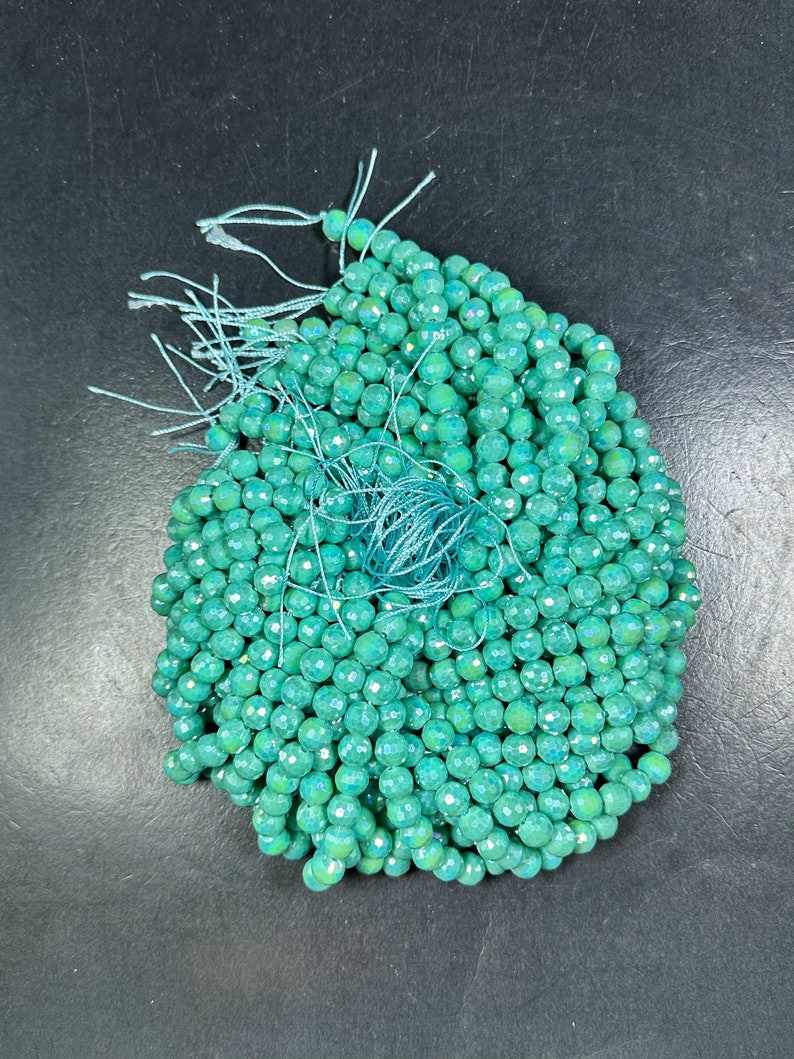 May include: A strand of teal blue faceted gemstone beads. The beads are round and have a smooth, polished finish.
