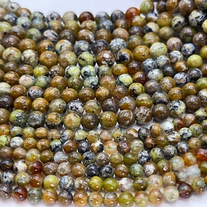 Op de afbeelding: Een streng ronde, groene, bruine en witte opaal kralen. De kralen zijn ongeveer 6 mm in diameter en hebben een natuurlijk, onregelmatig patroon.