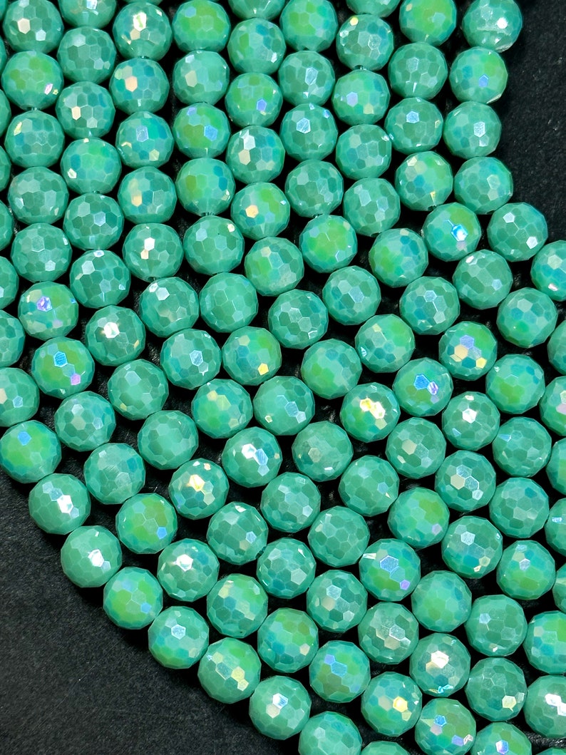 May include: A strand of iridescent green faceted glass beads. The beads are round and have a smooth, polished finish.