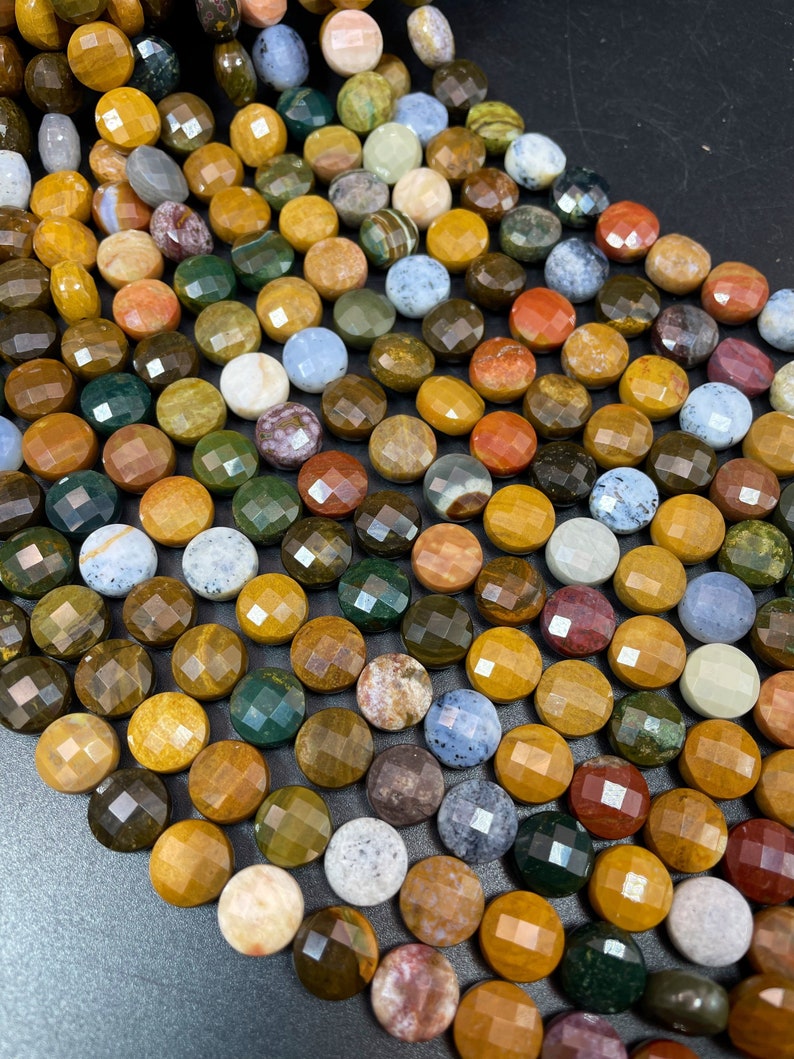 May include: A strand of multi-colored gemstone beads, each bead is faceted and round, with a variety of colors including brown, green, red, and blue.