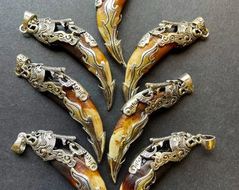 Lindo pingente em formato de dentes de lobo. Pingente de 10 x 50 mm com formato de dentes. Lindo pingente em tom bege-acastanhado natural. Com acabamento banhado a prata.