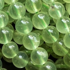 Op de afbeelding: Een streng ronde, doorschijnende groene kralen. De kralen zijn glad en hebben een lichte glans.