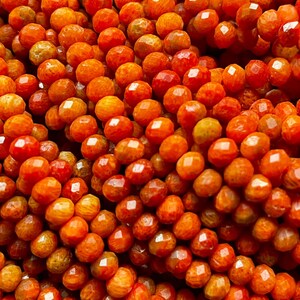 K&ouml;nnte beinhalten: Eine Str&auml;hne orangefarbener Korallenperlen mit einer facettierten, unregelm&auml;&szlig;igen Form. Die Perlen haben eine leuchtende orange Farbe mit einer leicht strukturierten Oberfl&auml;che.