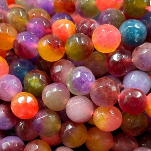 May include: A close-up of a strand of colorful agate beads. The beads are round and have a smooth, polished finish. The colors of the beads are a mix of pink, purple, yellow, orange, and green.