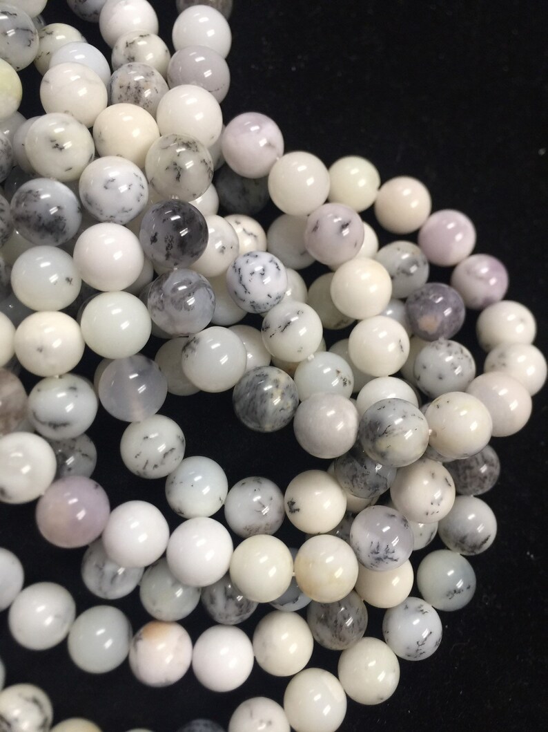 May include: A strand of white and gray dendritic opal beads. The beads are round and have a smooth, polished finish. The opal has a natural dendritic pattern, which gives it a unique and beautiful look.