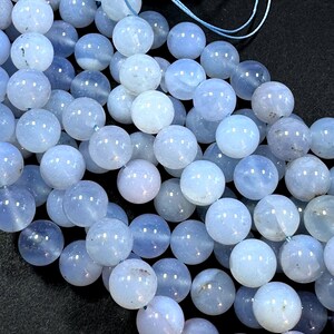 Pu&ograve; includere: Una collana di perle di agata blu chiaro, ogni perla &egrave; rotonda e liscia. Le perle sono infilate su un cordoncino blu sottile.