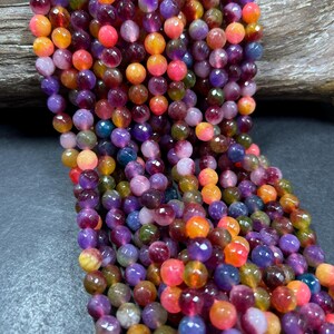 May include: A strand of colorful faceted gemstone beads. The beads are round and have a variety of colors, including purple, pink, orange, yellow, and green.