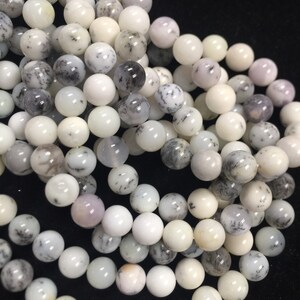 May include: A strand of white, gray, and black dendritic opal beads. The beads are round and smooth, and they have a natural, organic look.