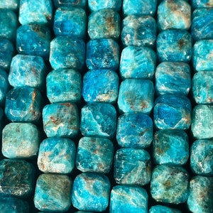 May include: A strand of blue apatite beads, each bead is faceted and has a square shape.