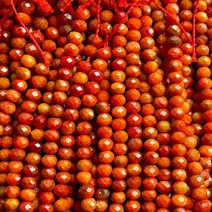 K&ouml;nnte beinhalten: Eine Str&auml;hne orangefarbener Korallenperlen, jede Perle ist facettiert und hat eine raue, strukturierte Oberfl&auml;che.