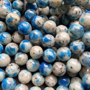 May include: A strand of blue and white kyanite beads. The beads are round and have a speckled appearance.