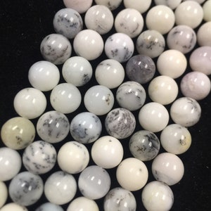 May include: A strand of white and gray dendritic opal beads. The beads are round and have a smooth, polished finish.