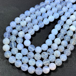 Pu&ograve; includere: Una collana di perle di calcedonio blu chiaro. Le perle sono rotonde e lisce, e hanno un aspetto leggermente traslucido.