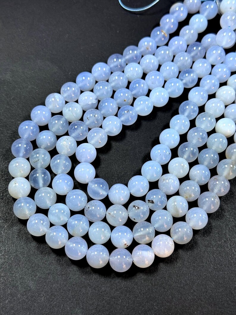 Pu&ograve; includere: Una collana di perle di calcedonio blu chiaro. Le perle sono rotonde e lisce, e hanno un aspetto leggermente traslucido.