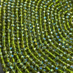 May include: A strand of green faceted glass beads. The beads have an iridescent finish.