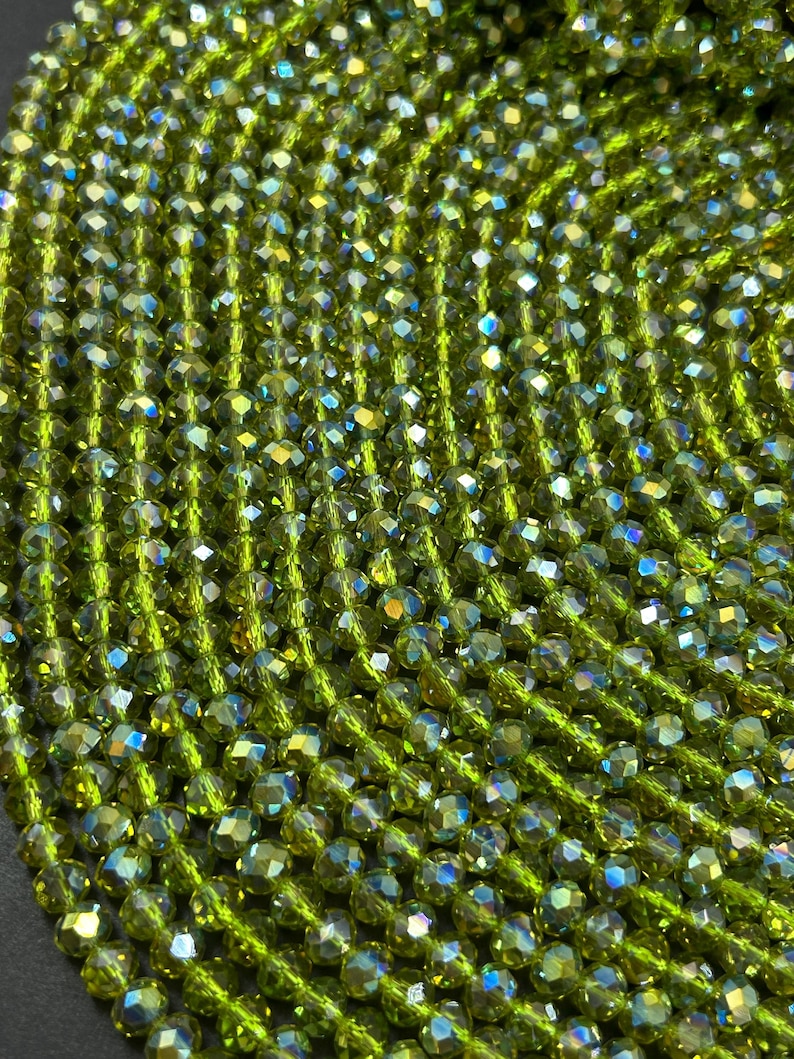 May include: A strand of green faceted glass beads. The beads have an iridescent finish.