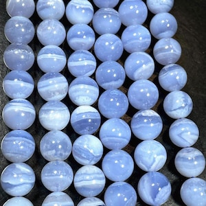 May include: A strand of blue agate beads. The beads are round and have a smooth, polished finish. The agate has a light blue color with white banding.